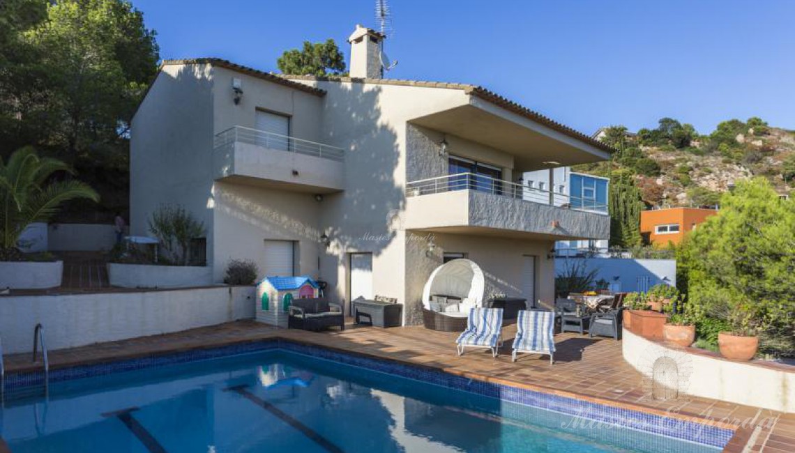 La casa desde la piscina, donde se aprecia la terraza solárium y el jardín