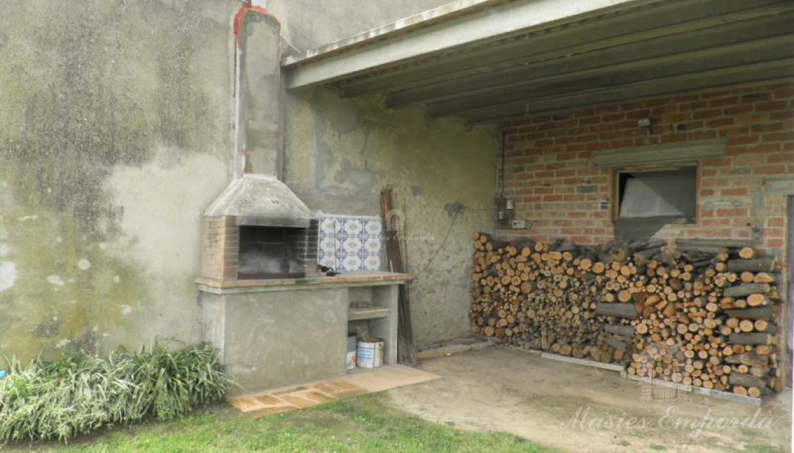 Detalle de la barbacoa y leñera del porche adjunto a la casa 