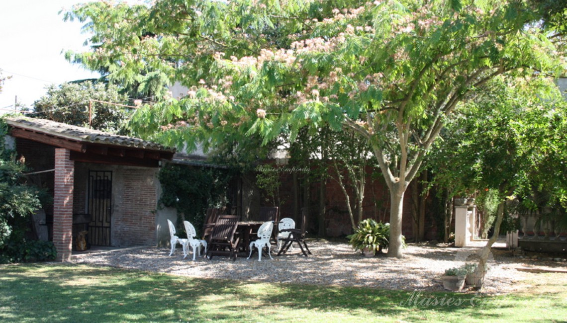 Zona de la barbacoa con porche cubierto en el jardín 