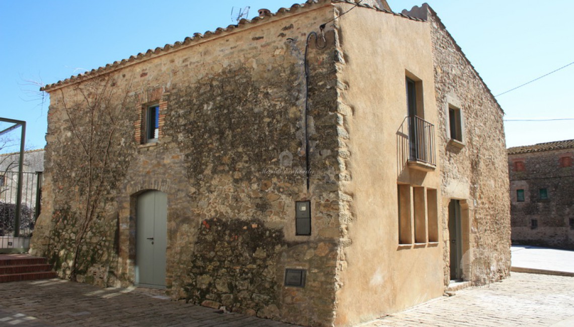 Vista de la fachada y el lateral de la casa de pueblo con entrada de vehículos en el lateral de esta 