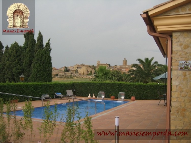 Vista de la casa, la piscina y el jardín con el pueblo al fondo de la imagen 