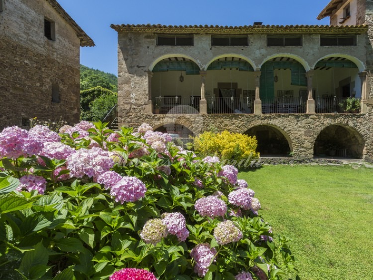 Detalle de fachada lateral de la masía con los arcos de piedra que dan cubierta a la magnífica terraza